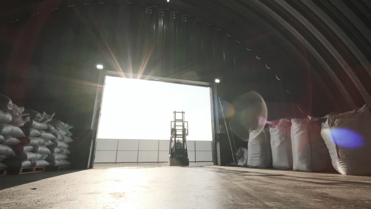 포크리프트 운전자가 창고에서 원재료의 큰 가방을 쌓고 있습니다.