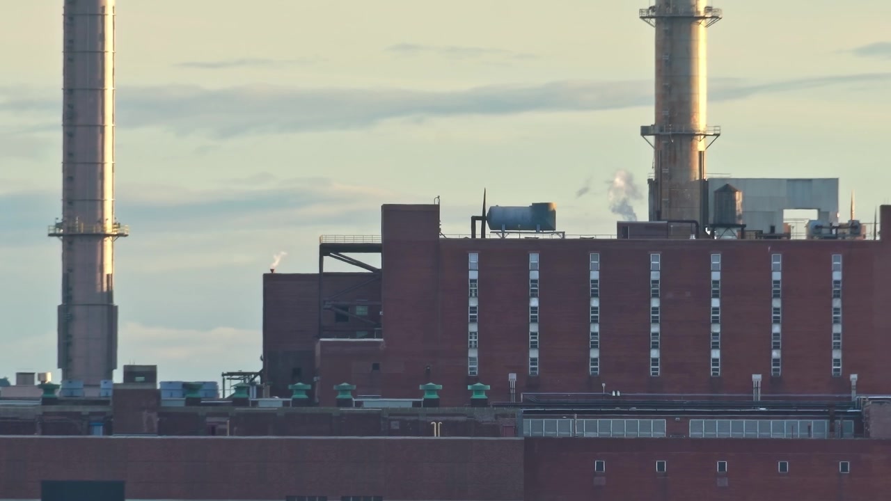 Fumo che sale da edifici industriali a New York City di sera