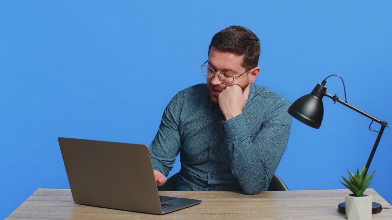 Upset tired man sitting at table using laptop having anxiety stress closing notebook finishing work