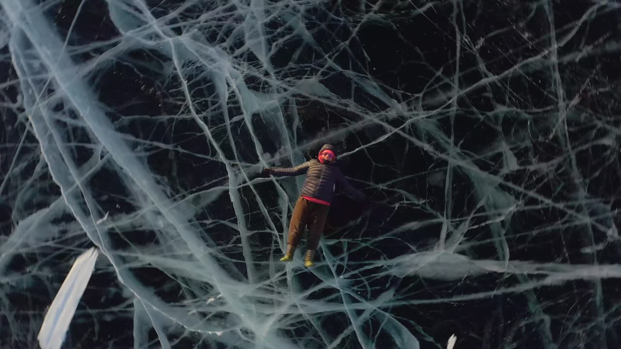 una niña yace en el hielo en invierno, agitando los brazos y las piernas hacia un lado, representando a un ángel.