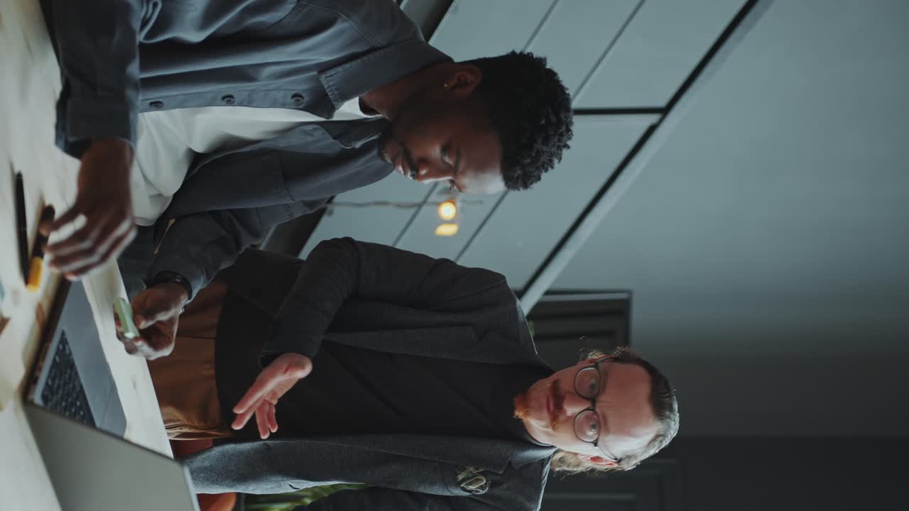 Businessman Explaining Project on Laptop to Coworker in Office