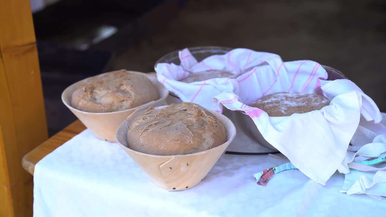 Freshly baked bread resting in wooden bowls on a cloth-covered table