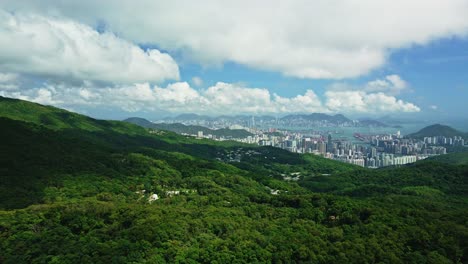 imágenes aéreas dinámicas a gran altura que revelan el paisaje urbano de hong kong rodeado de árboles, el mar y las montañas con hermosas formaciones de nubes en el cielo