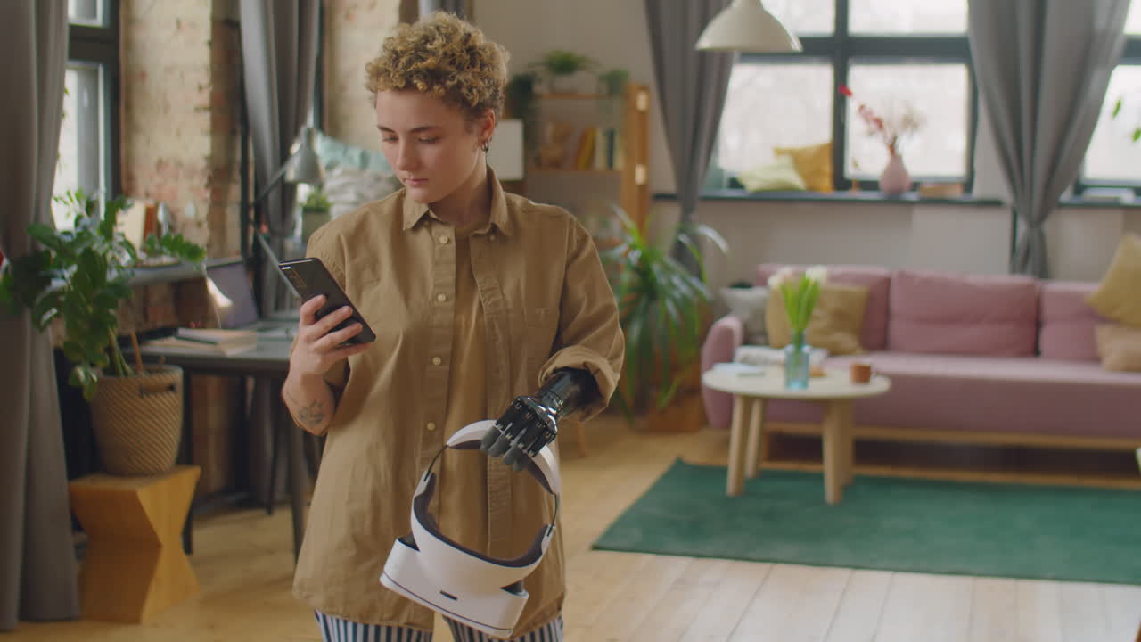 Girl with Prosthetic Arm Holding VR Headset and Using Smartphone at Home