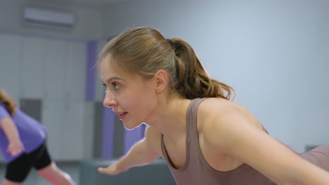 close-up of a focused fitness trainer guiding a young child as she struggles to maintain balance while standing on one leg during a training session in a modern gym