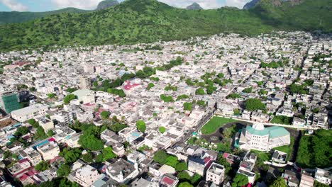 Barrio-Plaine-Verte-En-Port-Louis,-Mauricio,-Que-Muestra-Densas-Viviendas-Urbanas-Con-Exuberantes-Colinas-Verdes-Como-Telón-De-Fondo,-Día-Soleado,-Vista-Aérea