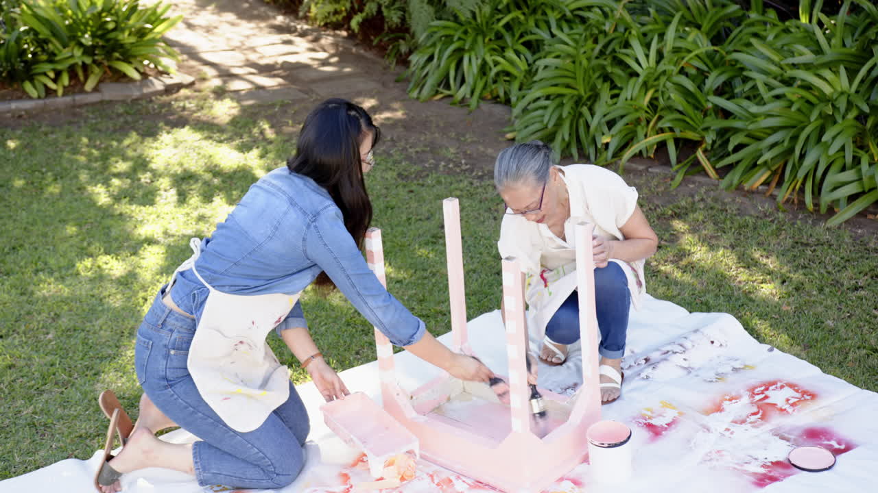 Painting furniture, asian grandmother and granddaughter together outdoors on sunny day, copy space