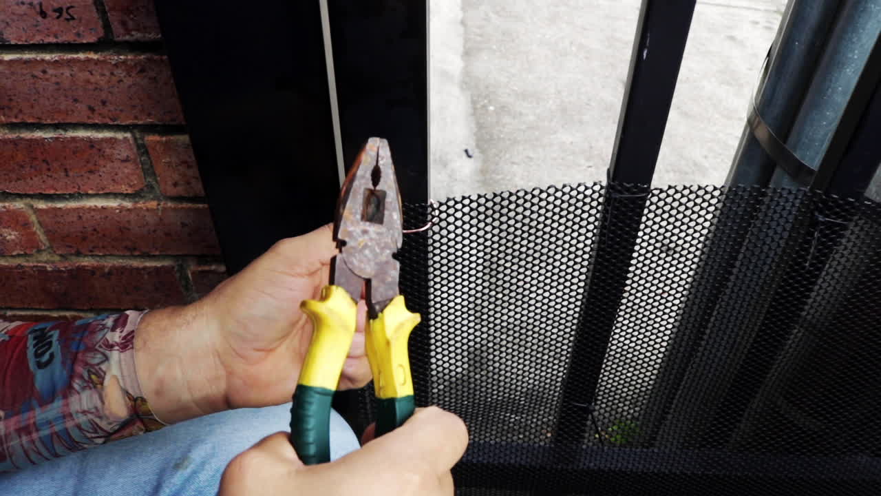 Man fixing a pet screen door mesh with a wire