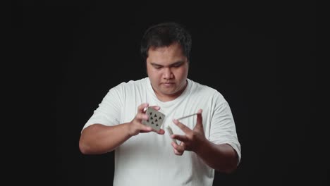 asian magician is making trick with cards, cardistry on black background