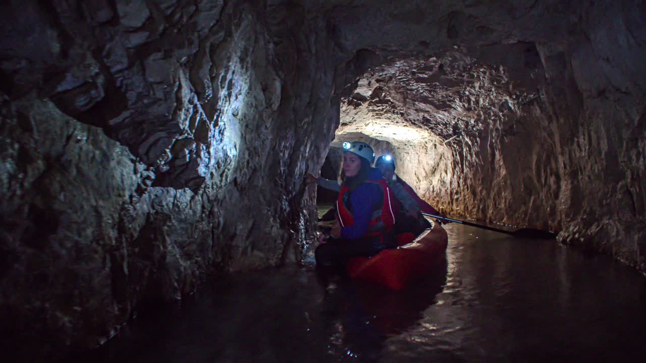 Tourists enjoying the underground kayaking at heritage site in old historic mine at Glančnik in Mežica. Low angle. View from back