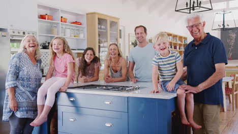 Retrato-De-Una-Familia-Multigeneracional-Parada-Juntos-Alrededor-De-La-Isla-De-La-Cocina