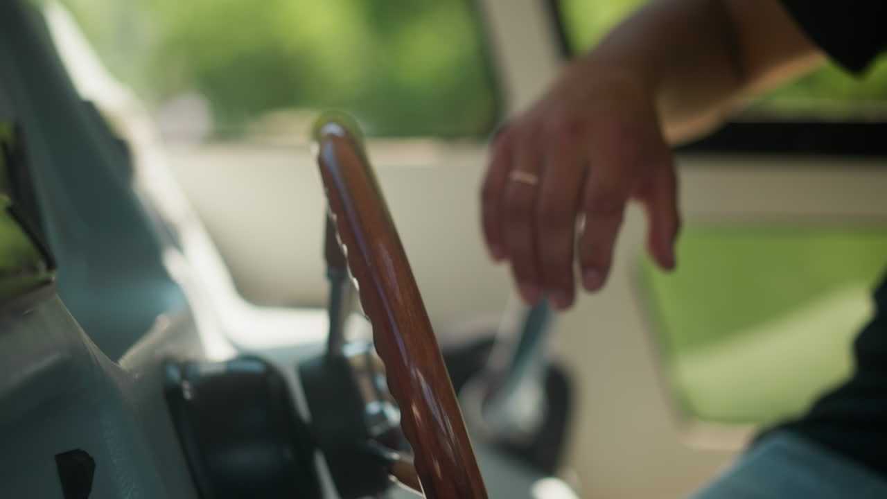 Skipper puts hand on luxury yacht with helm in pilothouse closeup. Yachtsman starts motor boat voyage on sunny day. Young man takes steering wheel