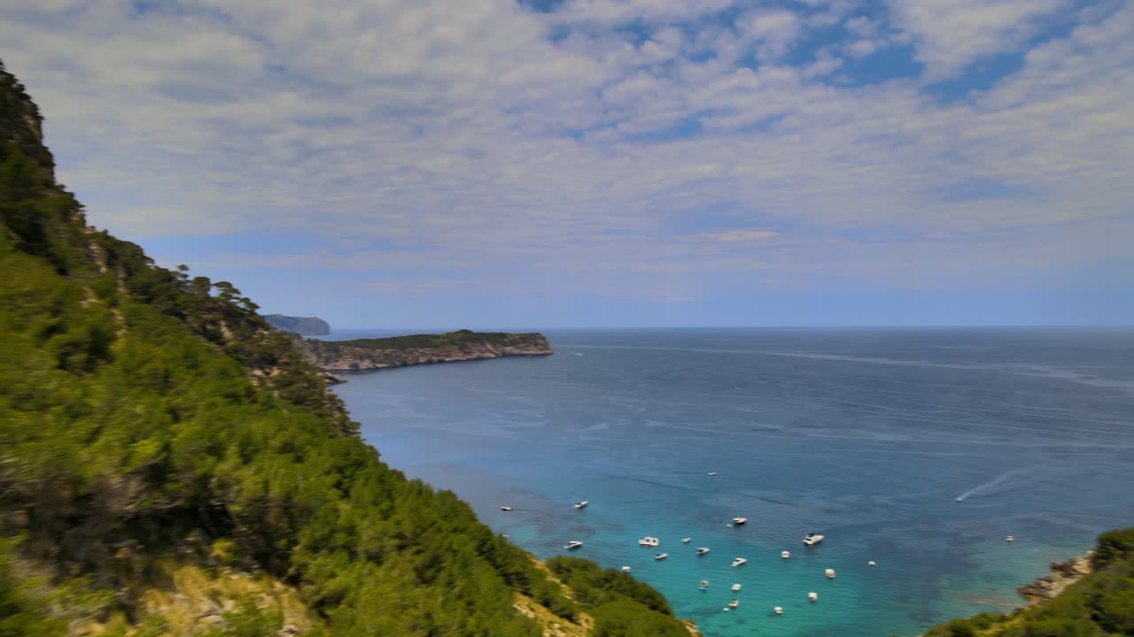 Discover the stunning coastline of Coll Baix, featuring lush greenery and clear blue waters. Boats bob gently in the harbor as the picturesque scenery captures the essence of Mallorca’s charm.