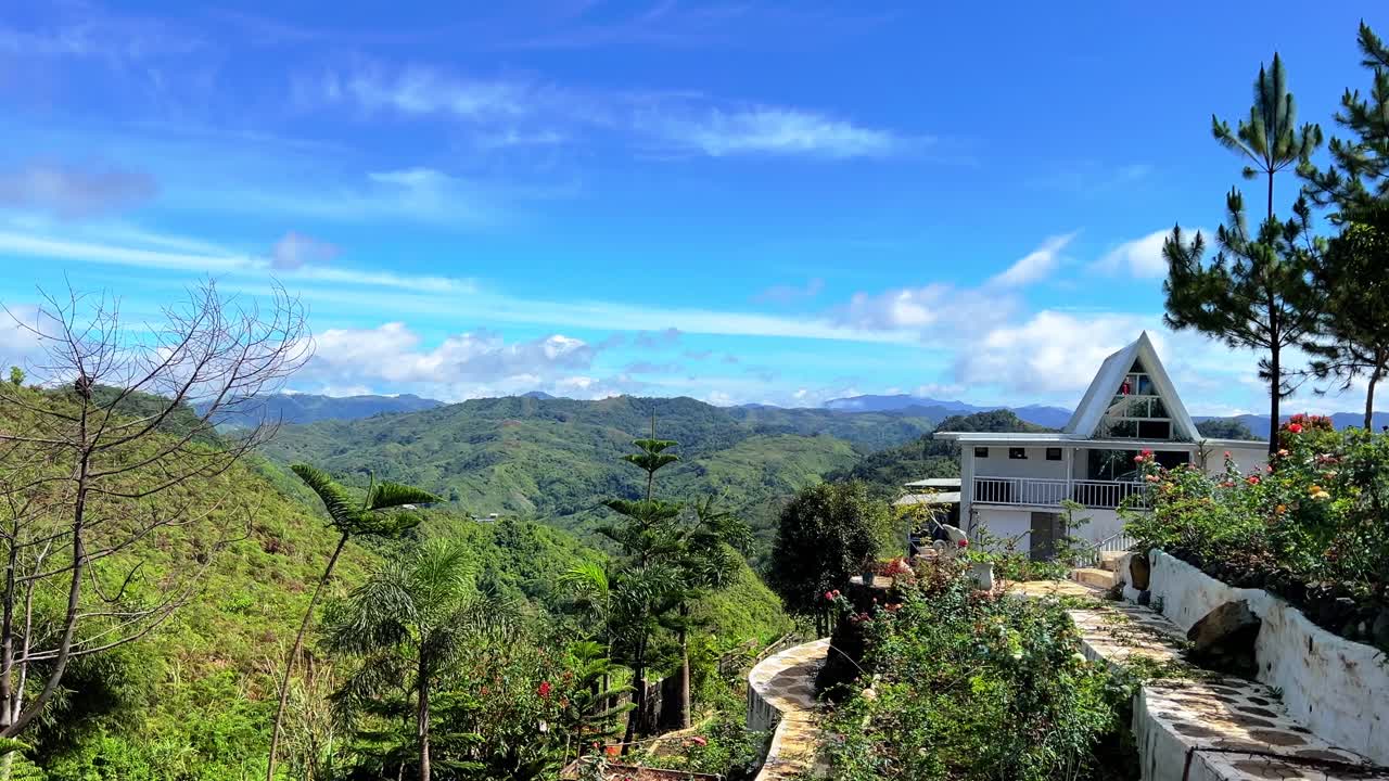Modern A-frame house surrounded by flowers and pine trees with panoramic mountain views, perfect for travel, architecture, and luxury lifestyle projects