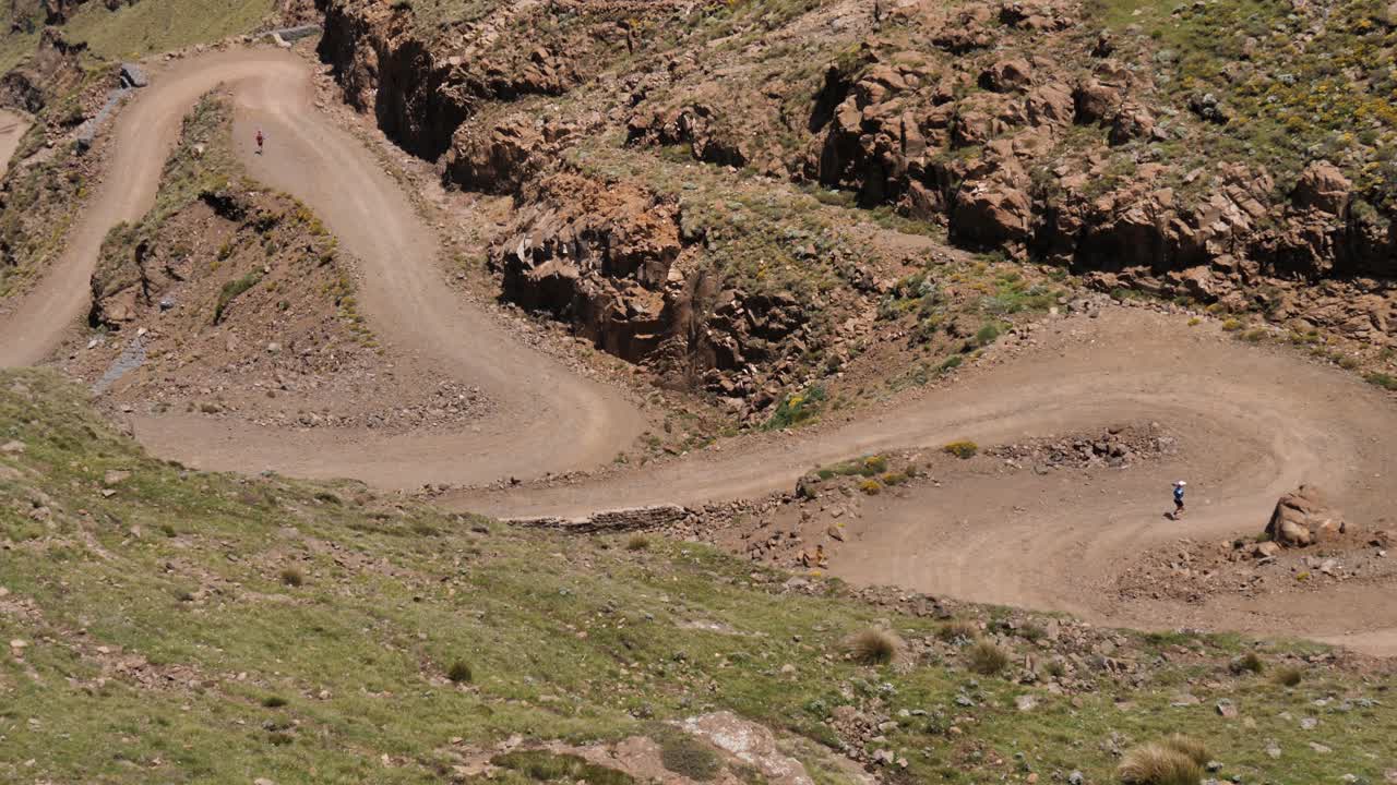 dos corredores descienden camino de zigzag de grava áspera de sani pass, áfrica