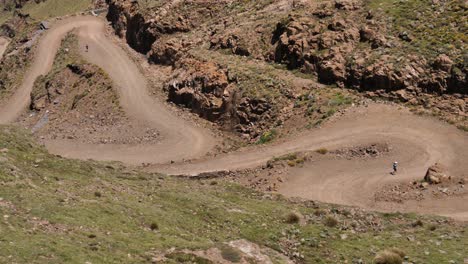 two joggers descend rough gravel switchback road of sani pass, africa