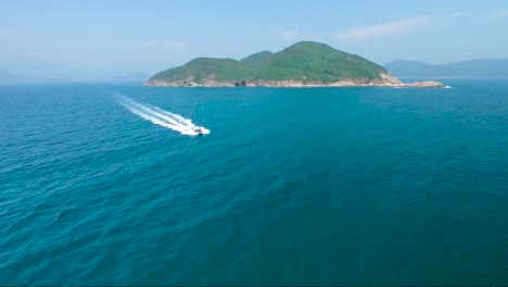 drone flying over the water and sea while a small motor boat passes through beneath it