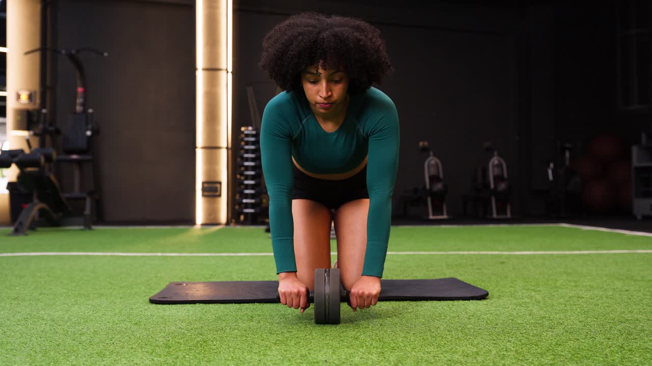 Woman Performing Ab Roller Exercise in a Modern Gym