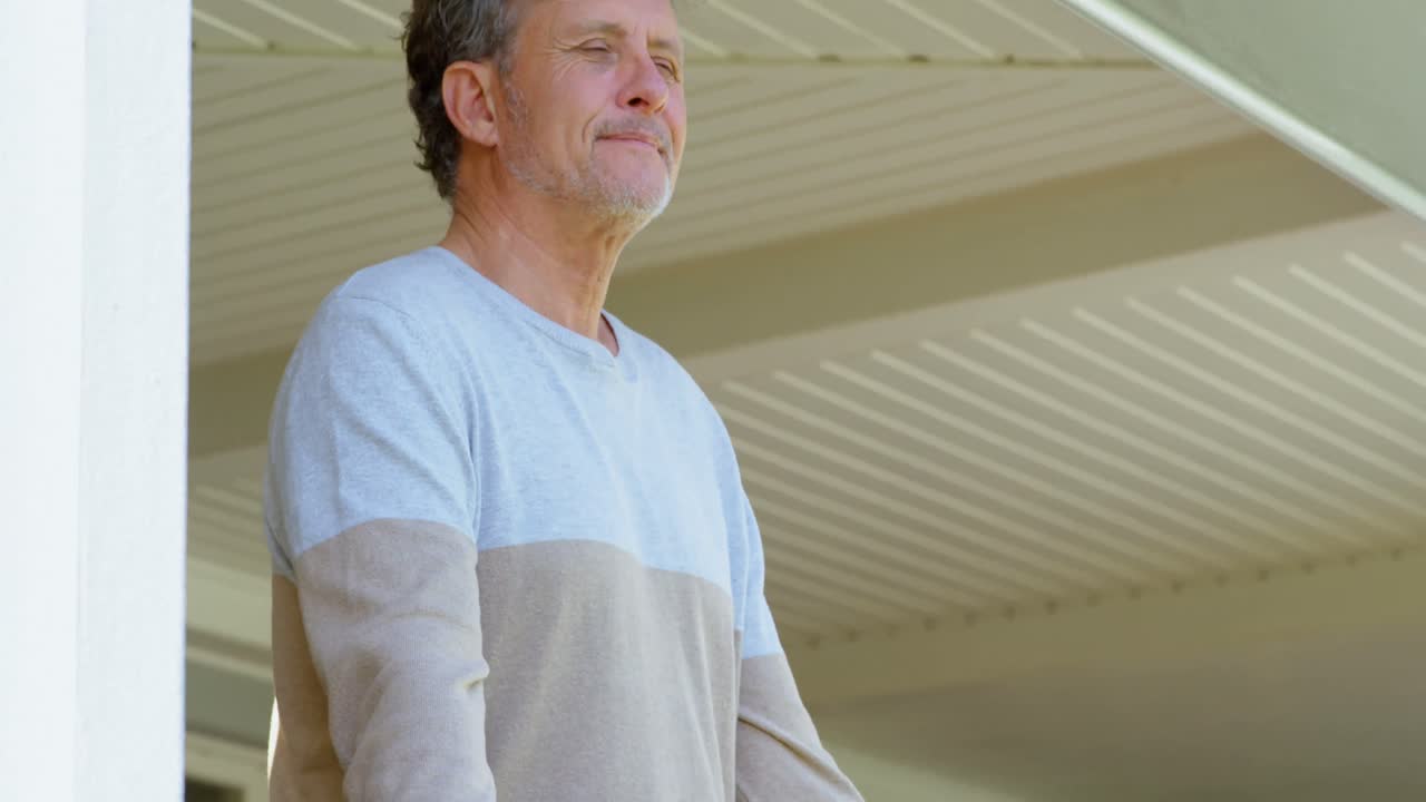 hombre mayor de pie en el porche en casa 4k