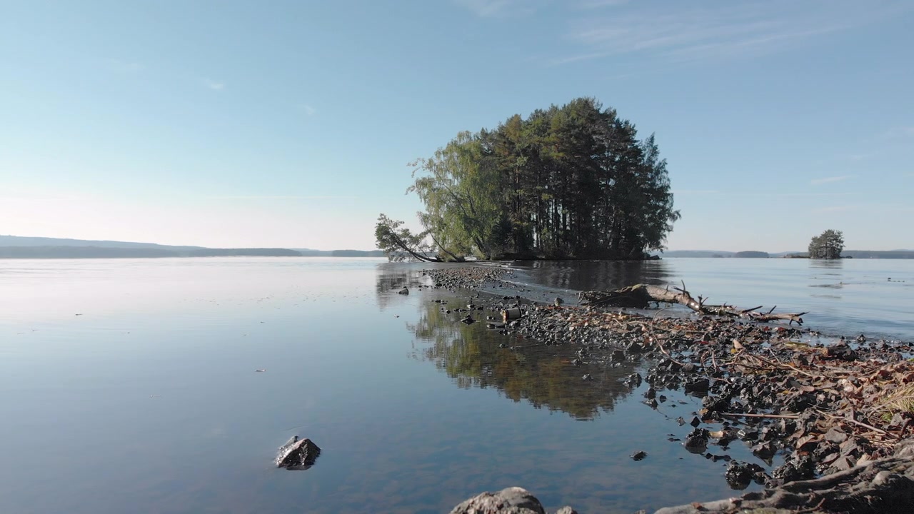Piccole onde che si infrangono sulla riva vicino a una piccola e bellissima isola