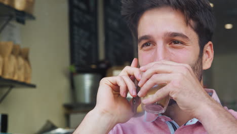 Young-Man-In-Coffee-Shop-Talking-On-Mobile-Phone