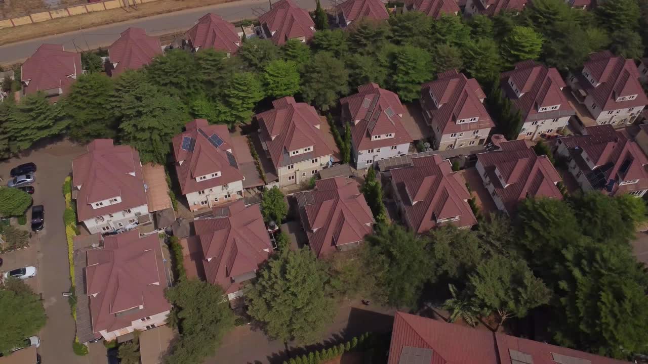 Magnifica ripresa aerea di file di case con tetti rossi in un tranquillo quartiere residenziale ad Abuja, Nigeria, in una giornata di sole