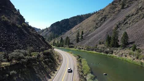 car driving on two lane road next to snake river in idaho rocky mountains