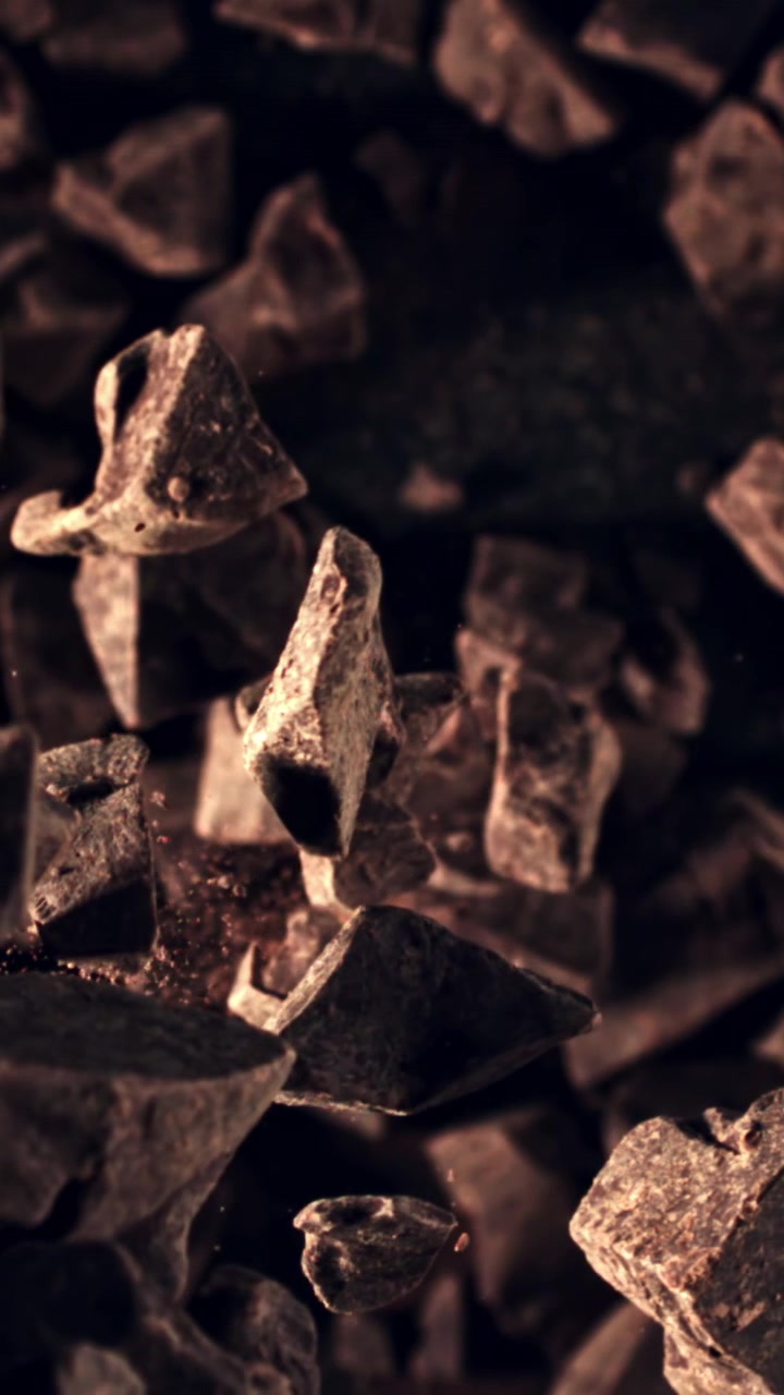 Trozos de chocolate cayendo a cámara lenta con polvo de cacao