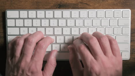 manos masculinas escribiendo texto en un teclado moderno blanco, primer plano
