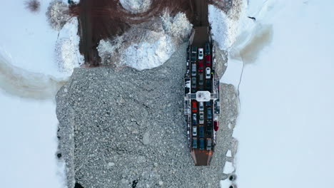 Top-down-winter-aerial-view-of-a-car-ferry-crossing-a-frozen-river