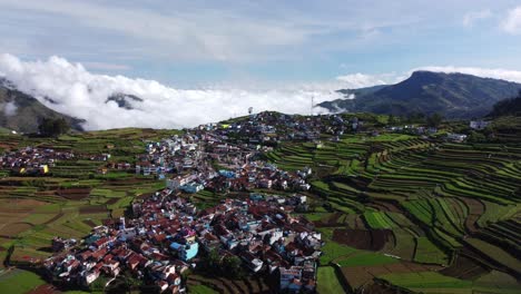 Panoramic-drone-shot-of-Poombarai-village-on-Palani-hills-with-clouds-approaching-the-valley,-Terrace-farming-fields-in-mountains,-Tamil-Nadu,-India