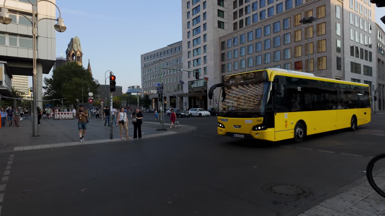 Evening in Berlin featuring a prominent electric yellow bus against an urban backdrop. Pedestrians and city life highlight the dynamic street scene.