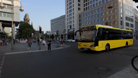 evening in berlin featuring a prominent electric yellow bus against an urban backdrop. pedestrians and city life highlight the dynamic street scene.