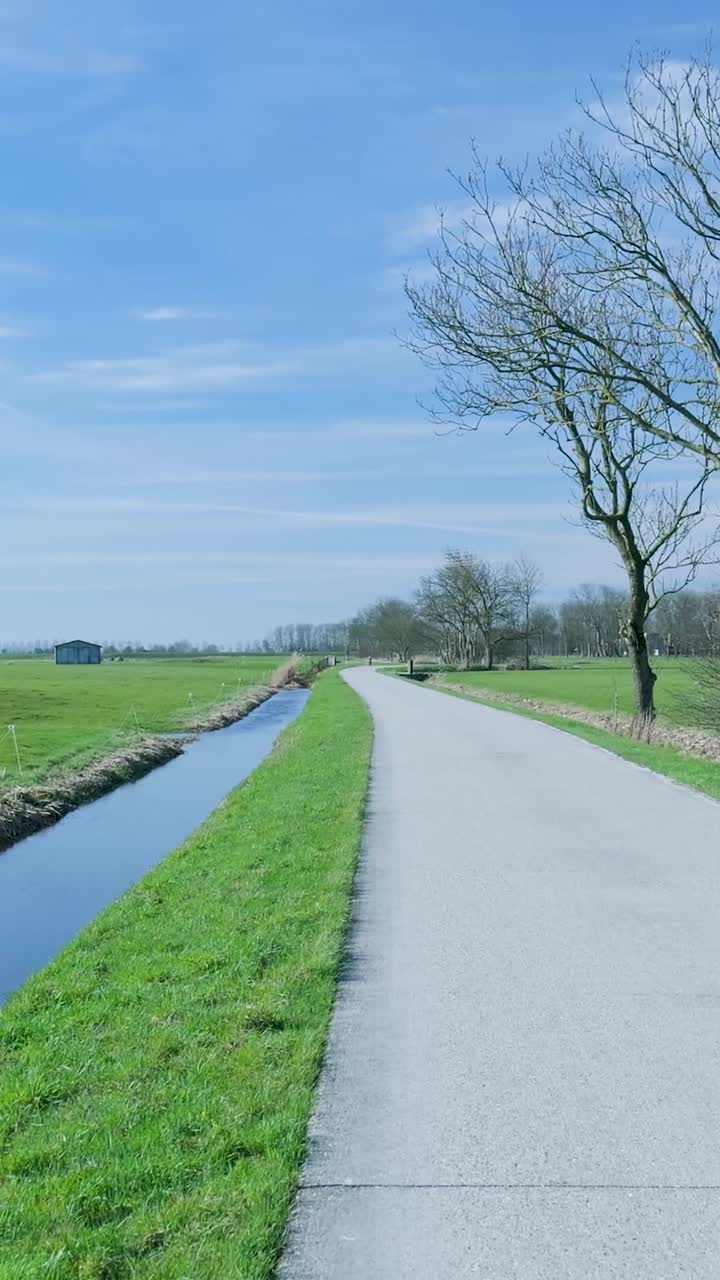 Lege landweg met kanaal en groene velden op een zonnige dag