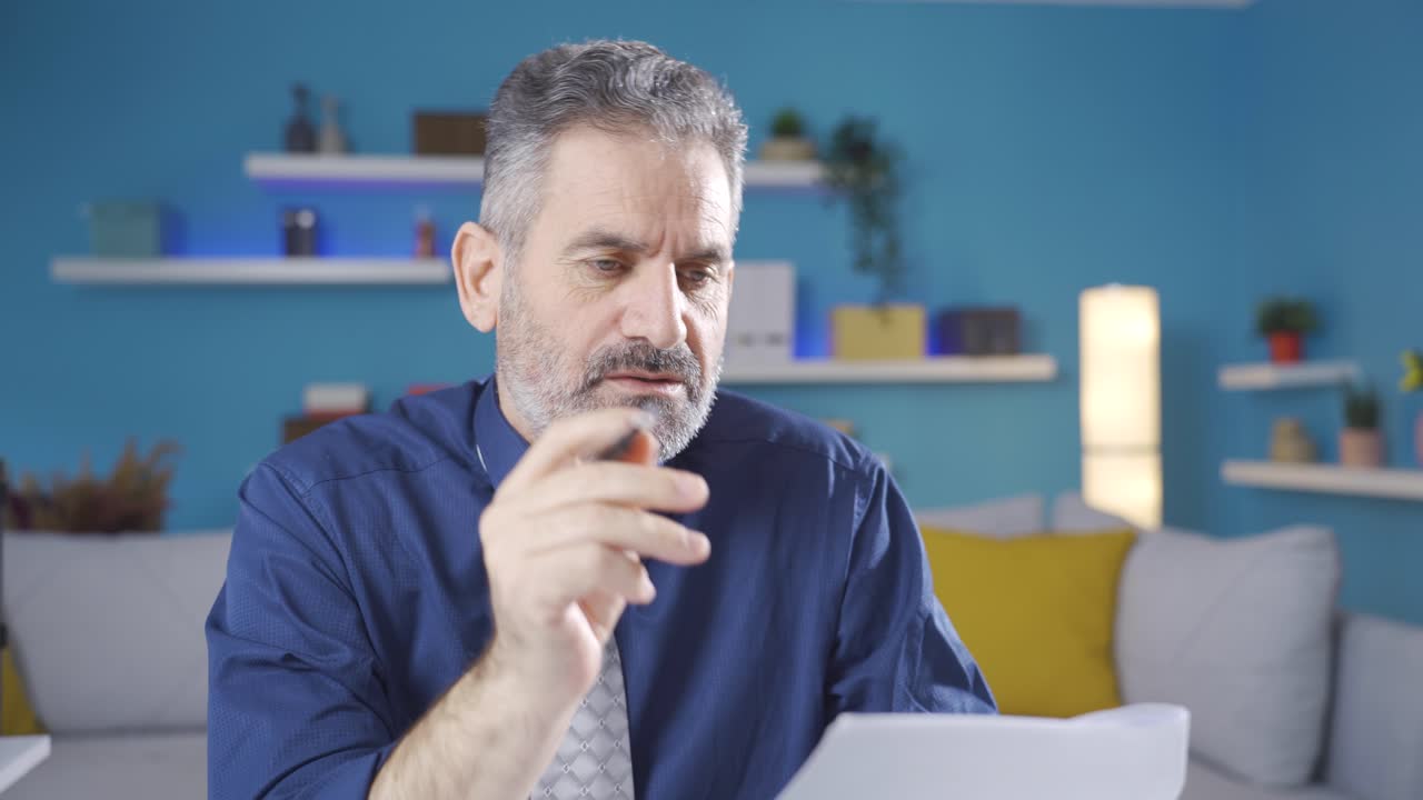 empresario que dirige su negocio desde casa piensa en lo que puede hacer sobre el negocio y toma notas en papel.