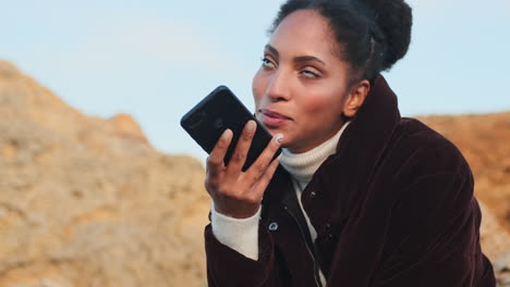 una chica afroamericana grabando un mensaje de voz en el teléfono.