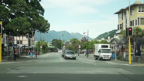 slowmo - luxury suv car driving along golf course in arrowtown, new zealand while golfers crossing road - aerial