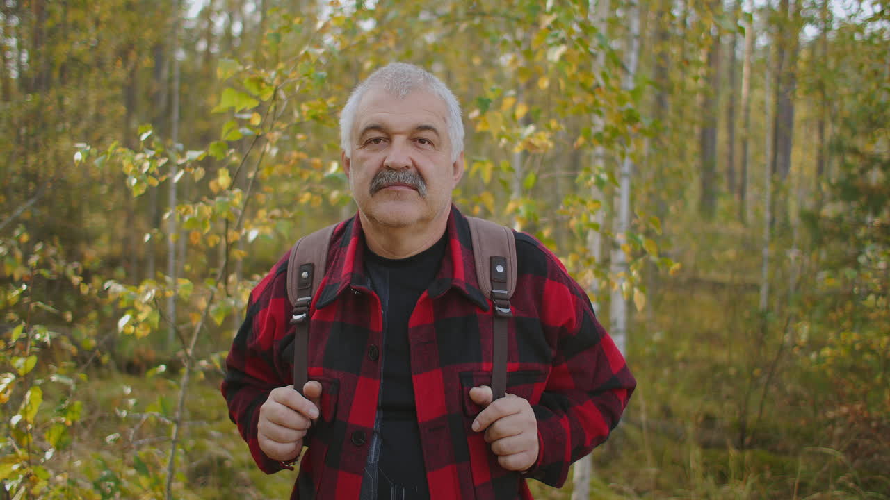 retrato de un excursionista de mediana edad con mochila en el bosque en el paisaje del día de otoño con follaje amarillo en los árboles