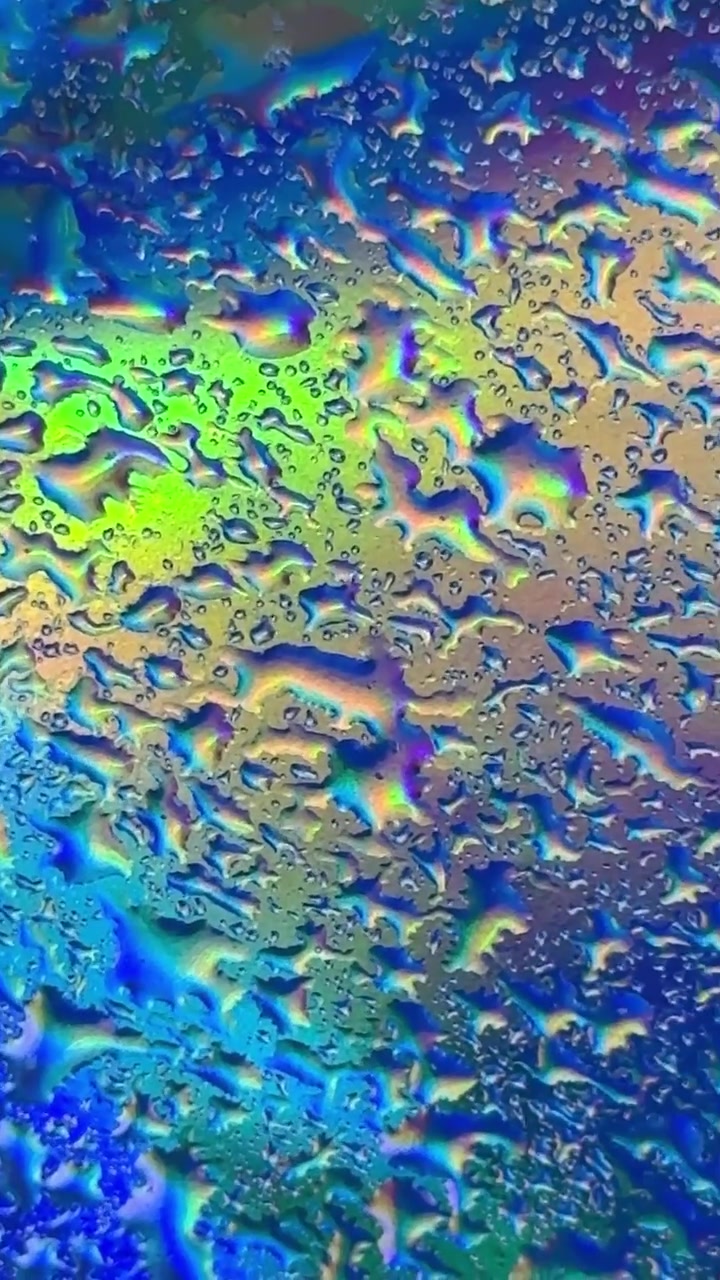 Makro záběr kapek vody na iridescentním povrchu