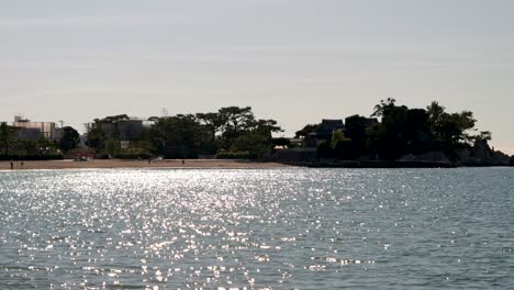 Glitzernden-Sonnigen-Ozean-Mit-Silhouetten-Von-Klippen-Im-Hintergrund