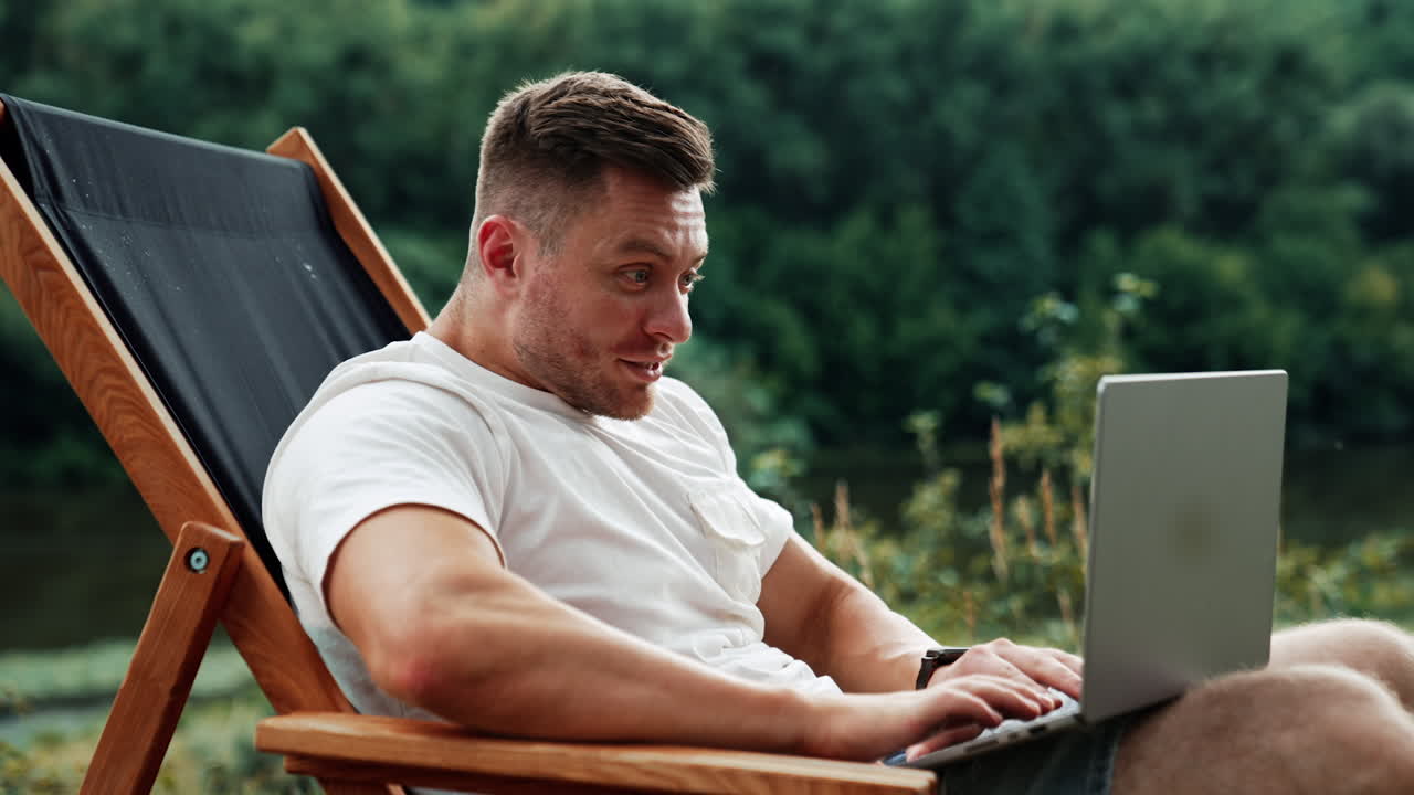 Caucasian man seems to be surprised looking at the screen of his laptop. Freelancer work remote in the nature on computer.