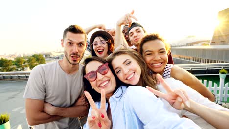 point of view shot of happy friends taking selfe on roof at summer party laughing, posing and enjoying good company. happiness, leisure and technology concept.