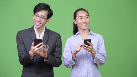 young asian business couple using phone together