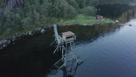 Toma-Aérea-Sobre-La-Antigua-Cabaña-De-Pesca-De-Salmón-En-Medio-Del-Lago---Laksegilje,-Noruega