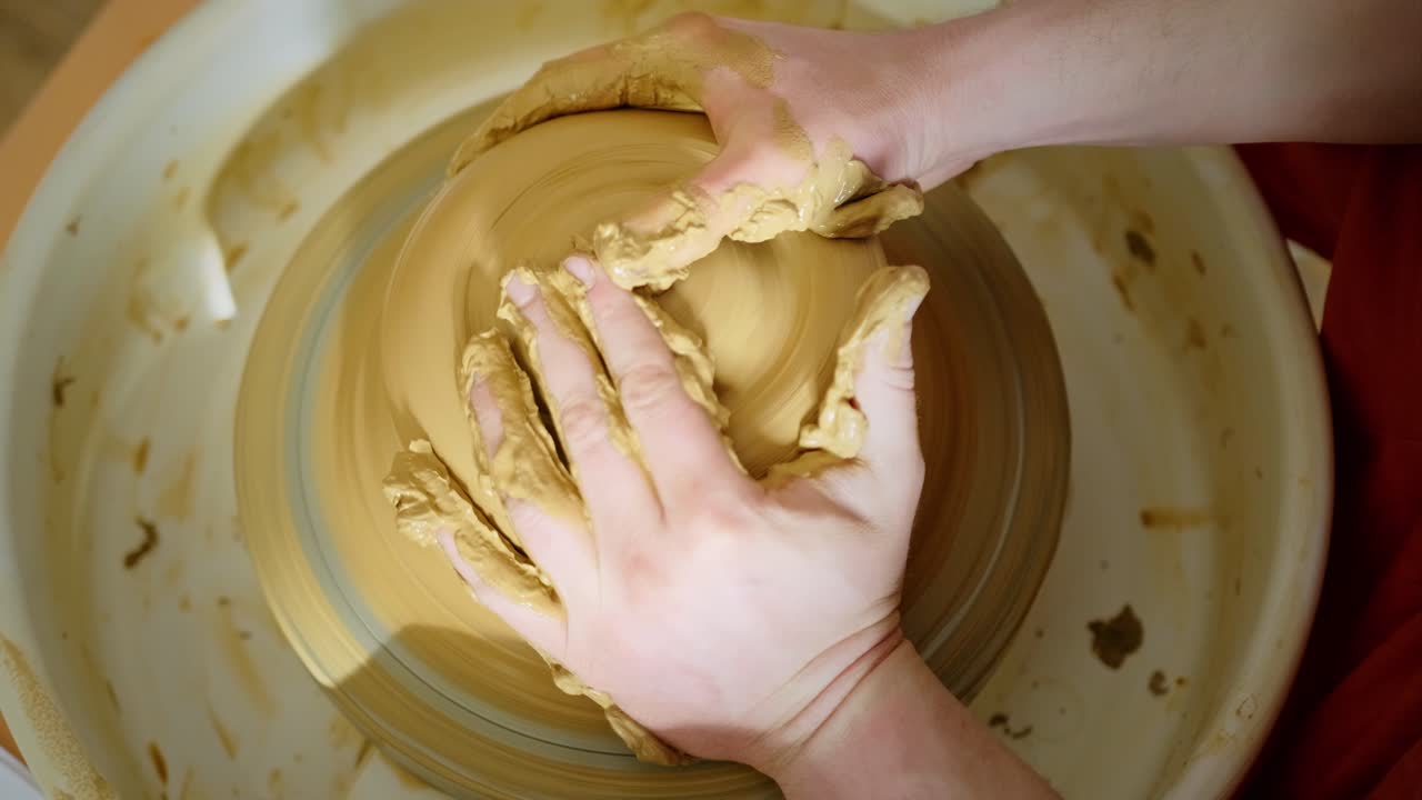 manos moldeando arcilla en una rueda de cerámica