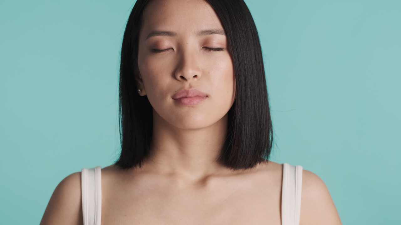 아시아 여성이 카메라 앞에서 깊은 숨을 쉬고 있습니다.