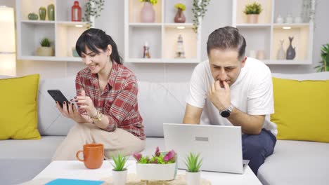 Pareja-Casada-Pasando-El-Rato-En-Una-Computadora-Portátil-Y-Un-Teléfono.-Uso-De-La-Tecnología-En-El-Hogar.