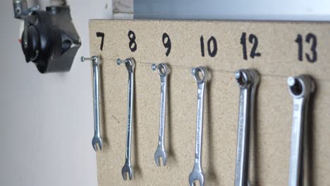 slow panning clip of organized wrenches hanging on a board in a workshop