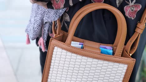 a close-up of a white woven bag with a brown leather strap