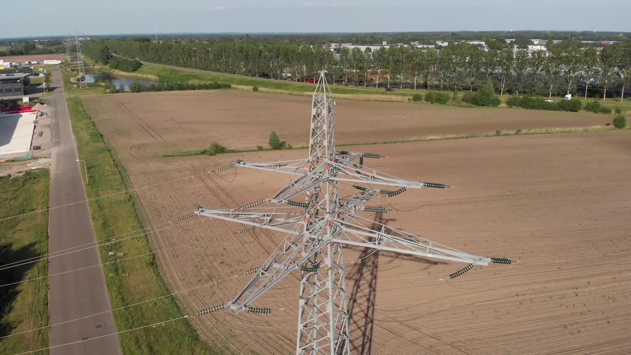 Transmission tower and power line energy supply in rural countryside setting, aerial view